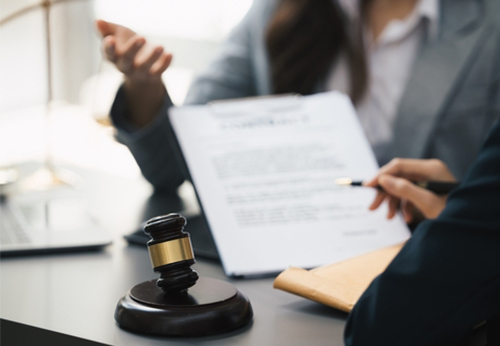 Close-up of a gavel and two people reviewing documents, symbolizing legal consultation