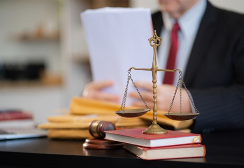 Scale of justice on legal books with a lawyer reviewing documents in the background, symbolizing legal services for Hardin County businesses