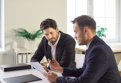 Two businessmen discussing a tablet, representing tailored business consulting services for Hardin County companies.